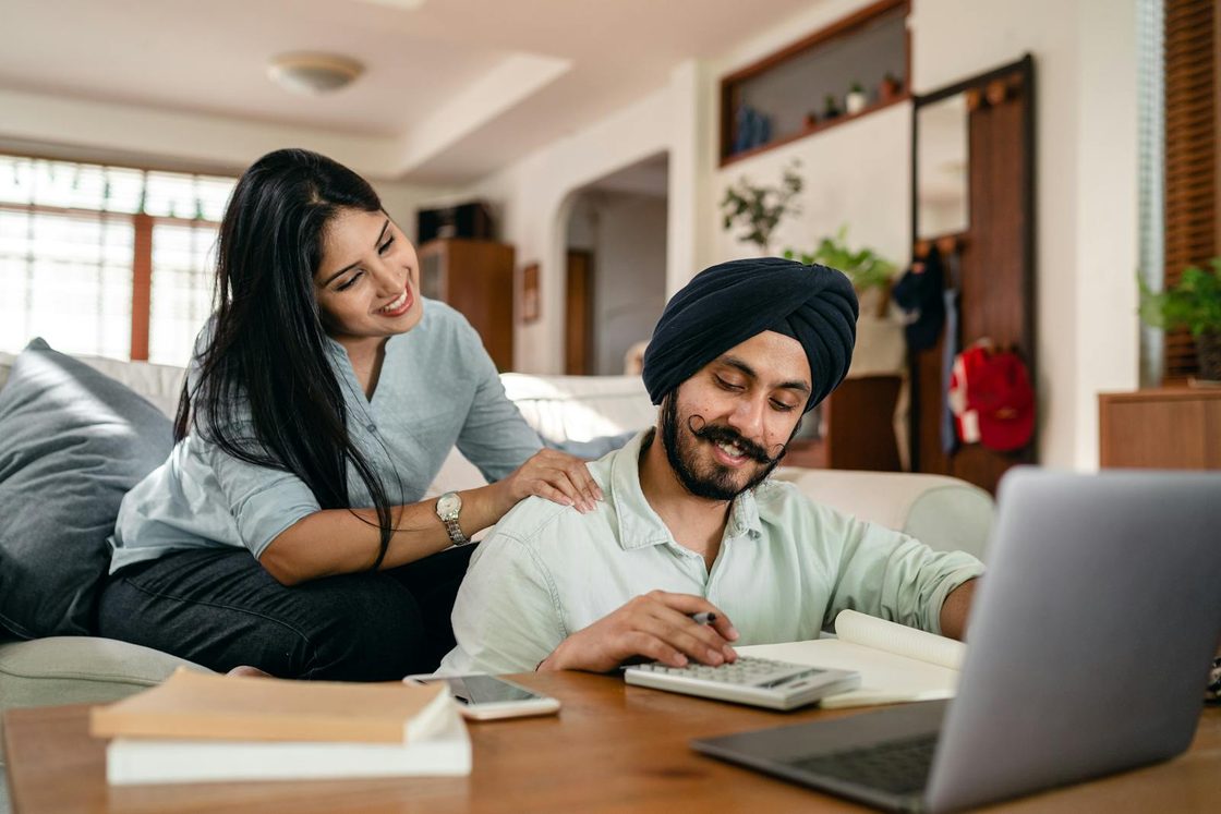 A couple smiling while reviewing their finances at home