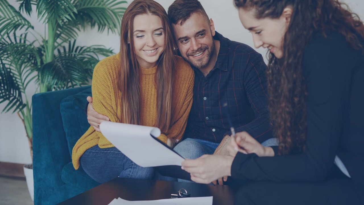 A financial coach reviewing a plan with a smiling young couple