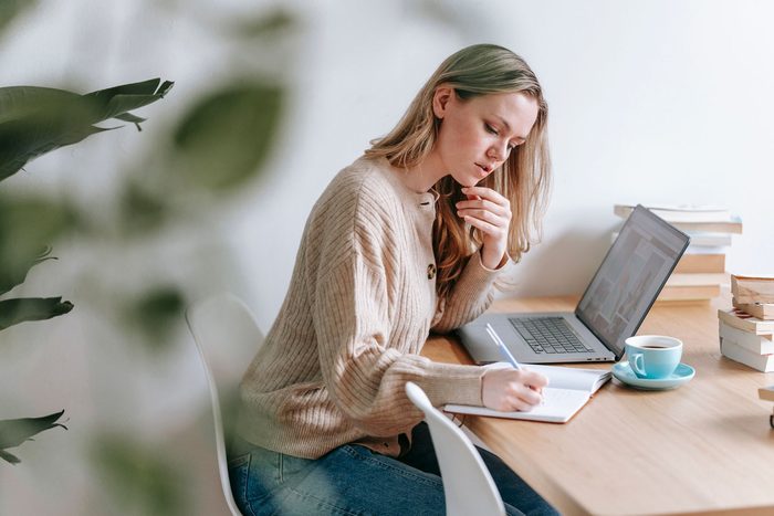 A woman writing out her financial goals in a notebook