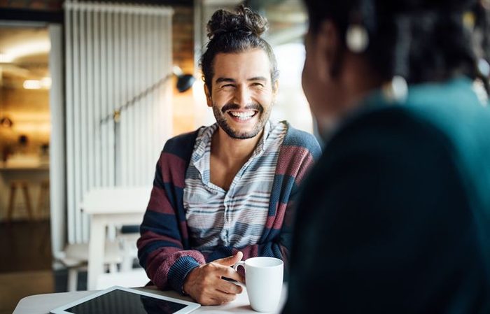 A coach and client talking over coffee